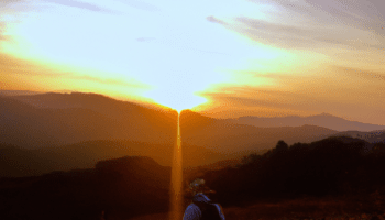 DALL·E 2022-12-03 03.22.34 – A vibrant photograph of a Japanese artisan hiking on a mountain, wide shot, outdoors, sunset photo at golden hour, wide-angle lens, soft focus, shot o